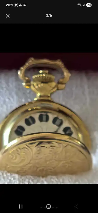 This is a ladies' Eska pocket watch featuring a gold-tone case with intricate floral engravings and...