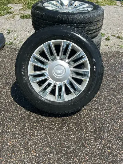 These are four used tires and rims from a 2009 Cadillac Escalade, perfect for replacing a set or hav...