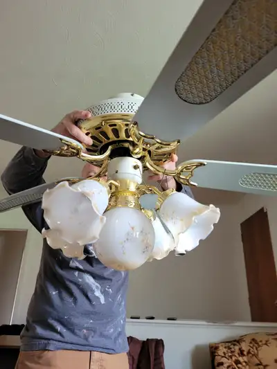 Five Blade Ceiling Fan. It is white in colour and has 4 chandelier bulbs with 1 regular bulb in the...