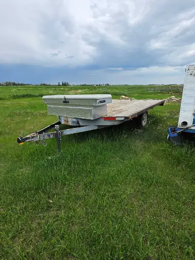 Durable flatbed utility trailer has a wooden plank deck and a black metal frame. This single-axle tr...