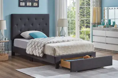 This is a used twin-size bed frame that features a grey upholstered headboard with button accents an...