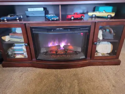 Wood cabinet with two glass doors on the ends. Electric fireplace insert, can change colours of the...