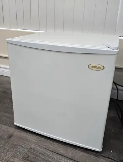 Small white refrigerator. Ideal for dorm rooms or small spaces. Features adjustable shelves and a do...
