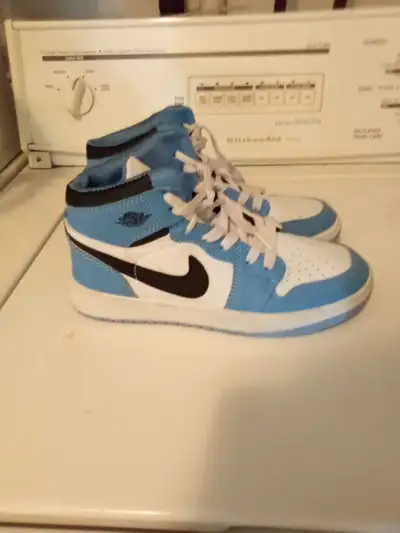 These are a pair of used, but still great looking, Nike Air Jordan 1 high-top sneakers in a baby blu...