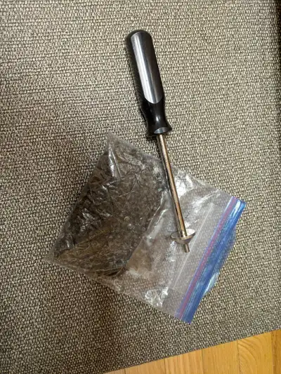 A bag of winter tire studs for a car/truck and a tool that can be used to install or remove studs. P...