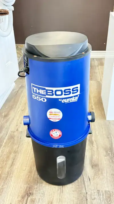 Powerful central vacuum unit is a blue and black Eureka The Boss 550 model. It has a cylindrical pla...