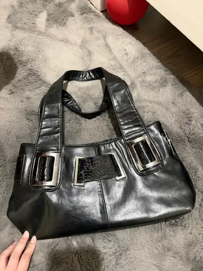 This classic vintage black handbag features a timeless design with silver-tone decorative buckle acc...