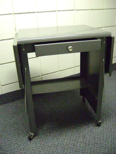 Small steel desk. top 20"x20" - 27"high - 39 1/2 " with sides up . Has drawer and wheels and shelf a...