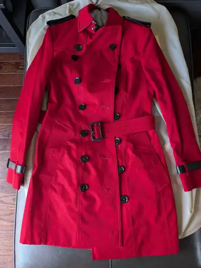 This is a stylish red Burberry trench coat, perfect for adding a pop of colour to your wardrobe. Thi...