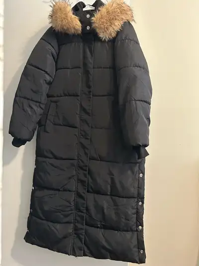 Bundle up in style with this long, black, faux-fur hooded winter coat, perfect for braving the Canad...