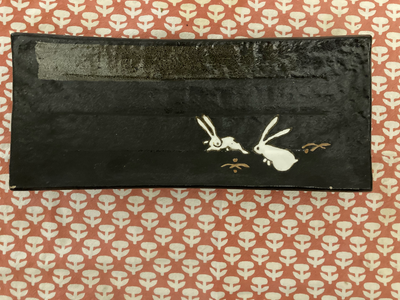 Slightly concave footed stoneware rectangular serving plate with rabbits motif from Tokyo design sli...