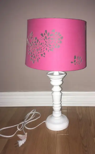 Beautiful white lamp base with dark pink ,cut-out detailing on the shade that casts a beautiful glow...