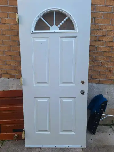 I'm selling a used exterior door, perfect for a home. The door is white with a decorative half-moon...