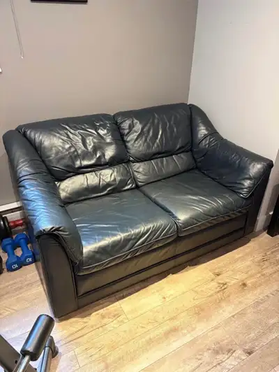 Upgrade your living space with this stylish black leather sofa and matching armchair set, perfect fo...