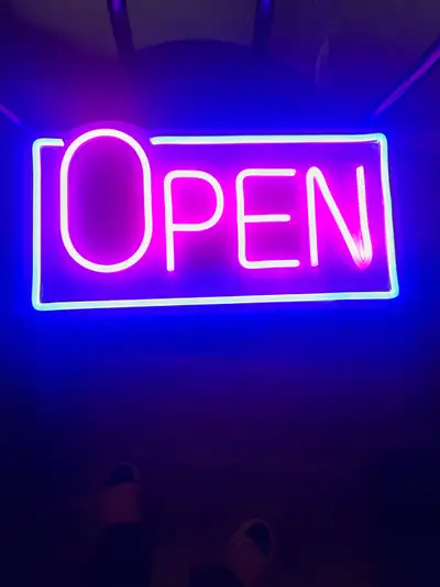 Selling a bright neon open sign, perfect for any business. The sign glows with vibrant pink and blue...