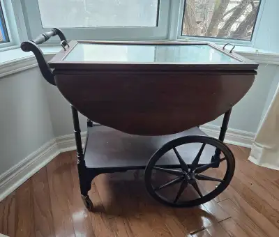 Charming cart with drop leafs. Has glass top, drawer and lower shelf for storage. Big spoked wheels...