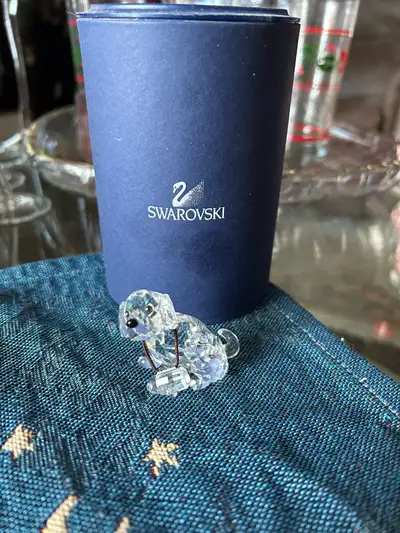 St. Bernard Puppy Swarovski Crystal Figurine wears an elastic band around its neck, which holds a sm...