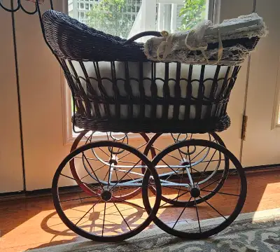 Charming vintage wicker doll carriage featuring a woven basket, a metal spoked undercarriage, and tu...