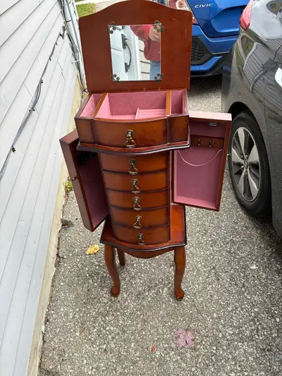 This is a used jewellery armoire with a rich, dark wood finish and pink felt lining, perfect for org...