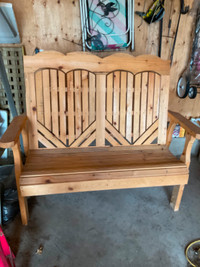 Adirondack type patio love seat made out of wood.