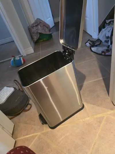 Rectangular stainless steel trash bin with a foot pedal for hands-free operation. It's a 10-gallon c...
