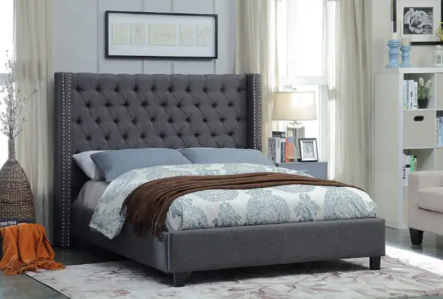 GREY FABRIC WING BED DEEP BUTTON TUFTING AND NAILHEAD DETAILS..