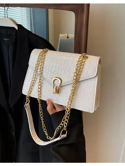 This stylish white crossbody bag features a chic crocodile pattern and a gold chain strap, perfect f...
