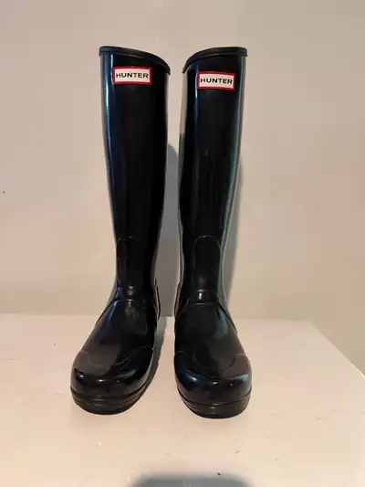 Gently worn, black, high-gloss Hunter rain boots, perfect for braving the elements while keeping you...
