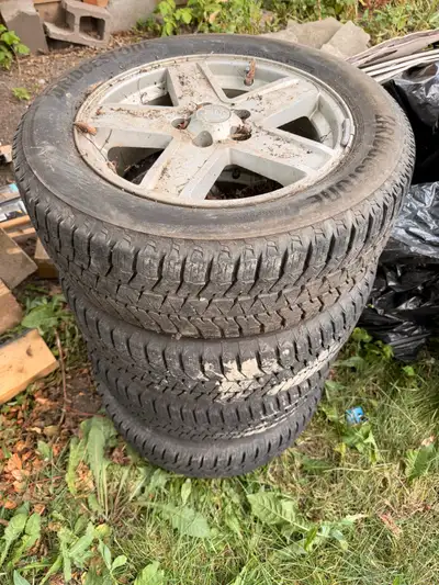 These Bridgestone tires mounted on Jeep alloy wheels are pre-owned and show signs of wear and age, a...