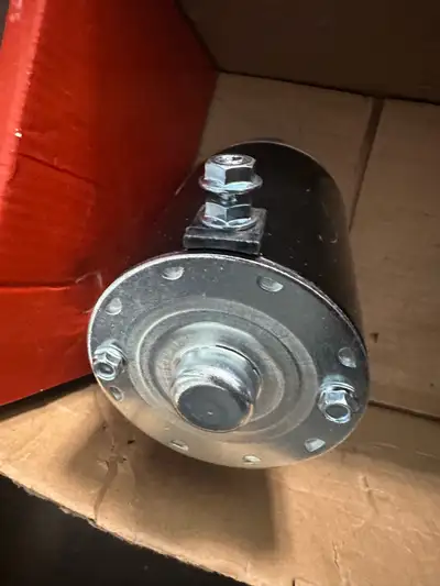 New starter motor for small engines. This part has a black cylindrical body with a silver-toned meta...