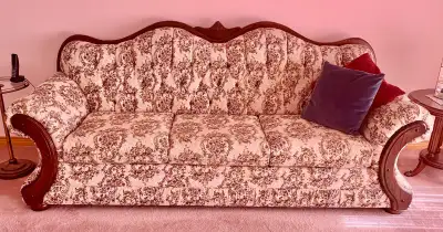 A French Provincial-style sofa and armchair set, made with a heavy, solid wood frame; and a floral-b...
