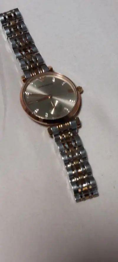 This is a used Emporio Armani watch with a two-tone band and a gold face. It is in good condition an...