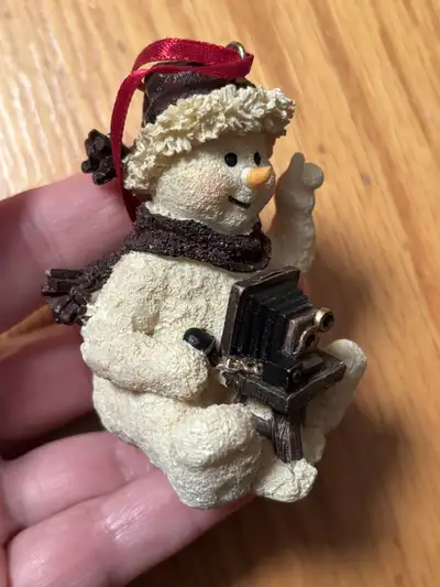 This is a preloved snowman ornament, posed as a photographer holding an antique camera. A charming a...