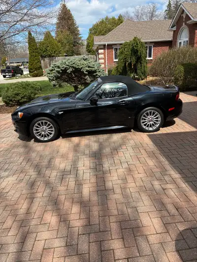 Experience the thrill of the open road in this sleek, black Fiat 124 Spider, boasting a manual trans...