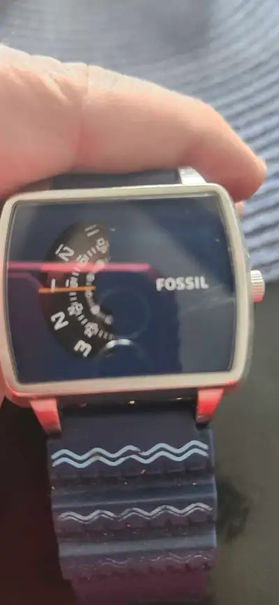 This is a stylish Fossil watch, featuring a unique dial design and a comfortable blue strap. It is i...