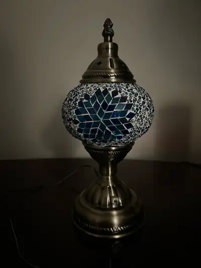 Stunning table lamp. Features a mosaic glass globe in shades of blue and white. Metal base and accen...