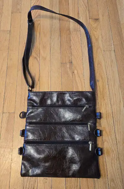 This is an Italian leather crossbow bag. that features three zippered compartments and an adjustable...