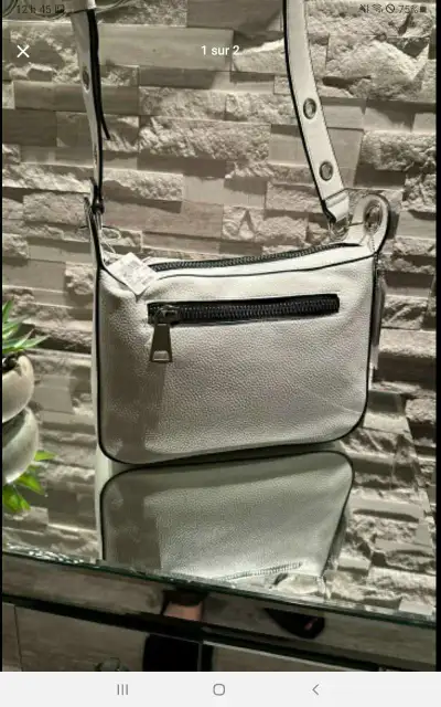 Découvrez ce sac à bandoulière blanc élégant, doté d'une fermeture éclair arrière pratique et d'une...