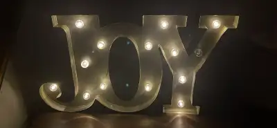 Add a touch of warmth to any room with this 'Joy' marquee light! It features a golden finish and bat...