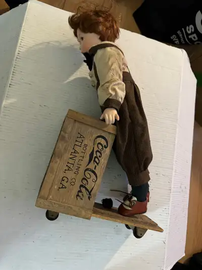Antique Coca cola porcelain doll on wooden cart, View more