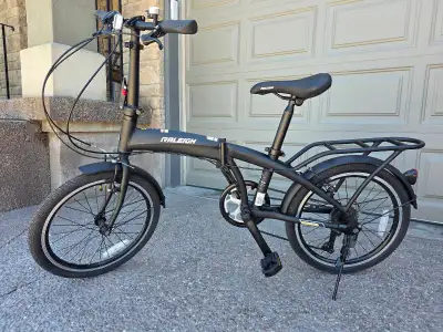 Black Raleigh folding bike. Bike has a folding design, rear rack, and fenders. 20 in wheels. Like ne...