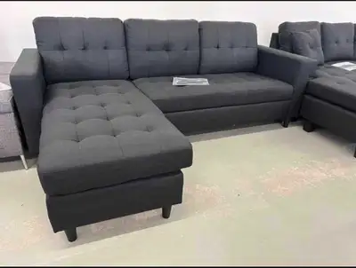 This stylish dark grey sectional sofa features a modern design with tufted cushions and a versatile...
