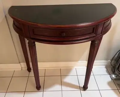 This hall table features a half-moon design with a sleek, dark top and elegant wood finish, compleme...