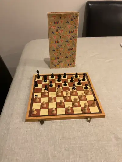 A vintage folding chess set with brass hinged/closeures, and the original decorative box. It is full...