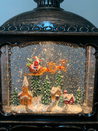 Snow globe lantern with Santa flying over a village