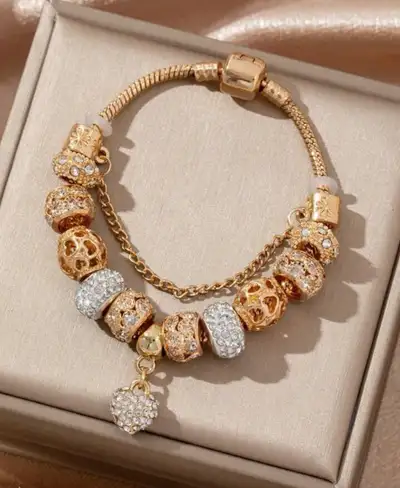 This is a used, but beautiful, gold-tone bracelet with multiple charms, including a heart. It is in...
