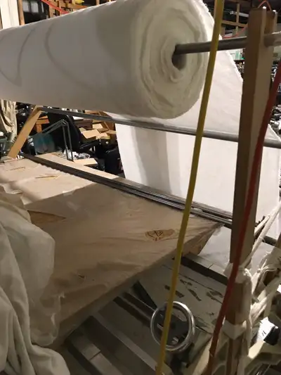 Fabric spreader for laying fabric on table in multiple layers. Fabric pieces can be cut in stacks of...