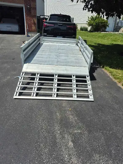 This pre-owned Stirling aluminum utility trailer features a 5ft x 7.4ft deck, a rear loading ramp, a...