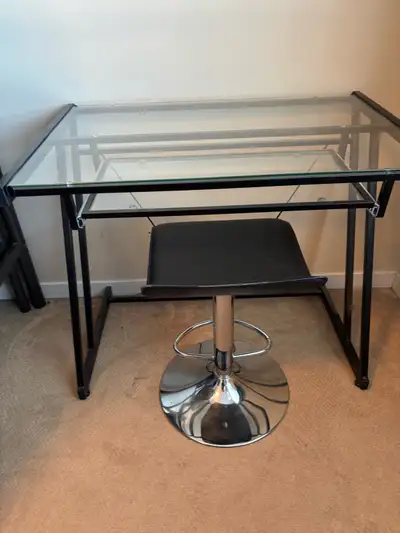 This glass computer desk features a sleek design with a black metal frame and a glass top. It's a st...