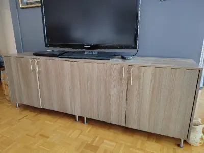 Stylish TV stand, four doors, ample storage. Light brown woodgrain finish. Metal legs. Great conditi...